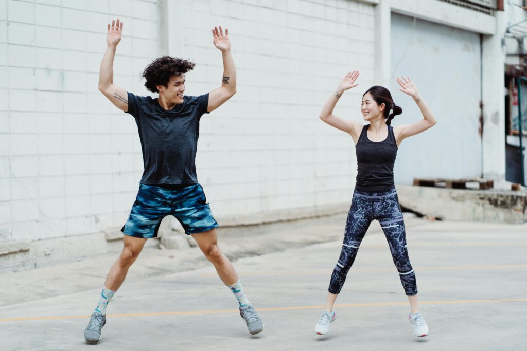 Man & Women doing jumping jacks as part of morning exercises at home to increase heart rate and stamina